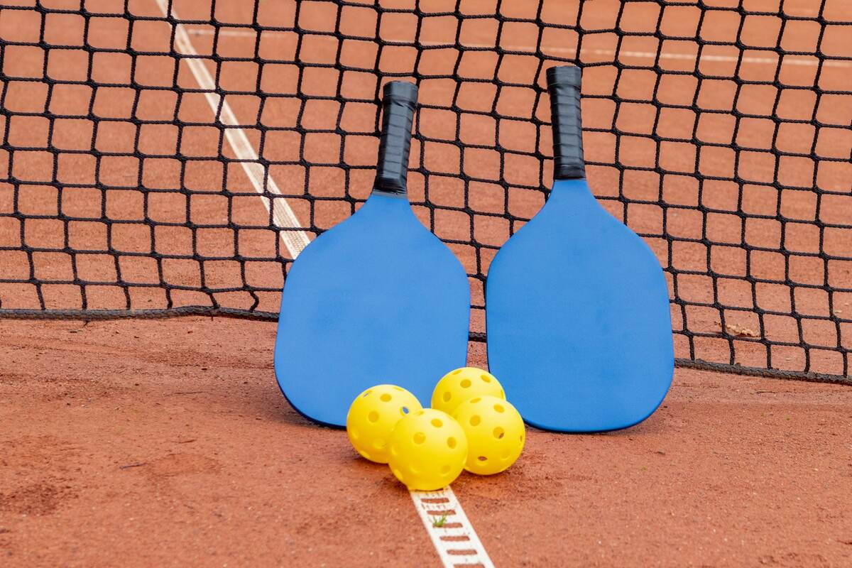 Pickleball paddles and balls resting against the net