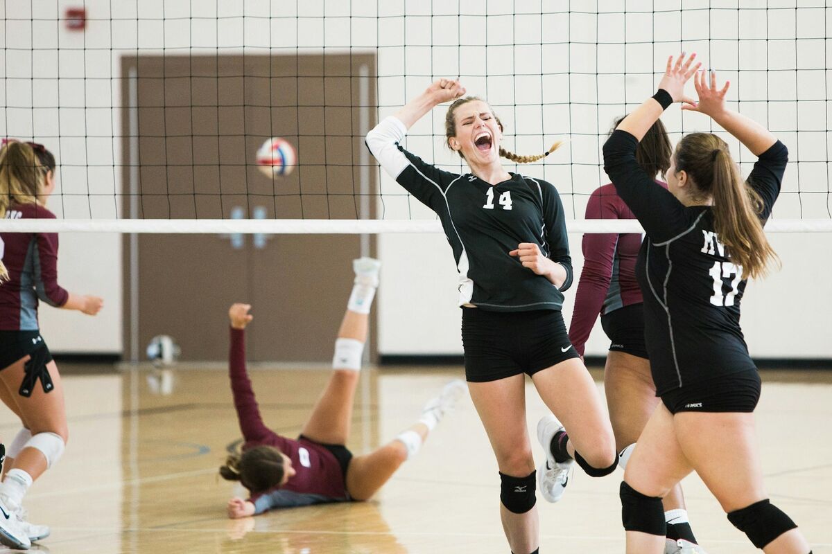 Volleyball players celebrating a point at the net